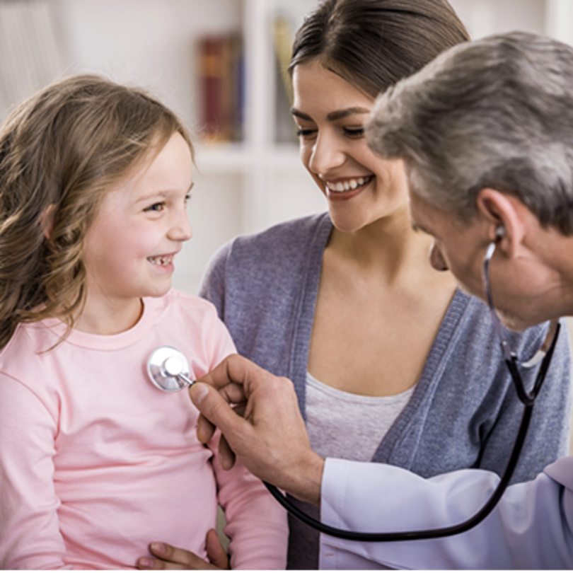Doctor using a stethoscope on a little girl with her mother