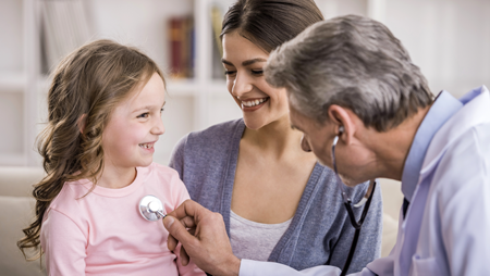 Doctor using a stethoscope on a little girl with her mother