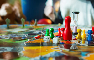 Mehrere Spieler sitzen um ein Brettspiel, das auf dem Tisch liegt, und genießen eine unterhaltsame und gesellige Spielrunde.