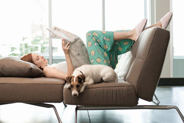 A woman reclines on a couch, enjoying a peaceful moment with her dog, embodying comfort and companionship