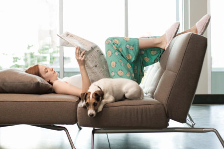 A woman reclines on a couch, enjoying a peaceful moment with her dog, embodying comfort and companionship