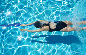 Eine Frau in einem Badeanzug schwimmt entspannt in einem klaren Pool.