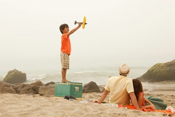 Child playing with a toy plane on a beach