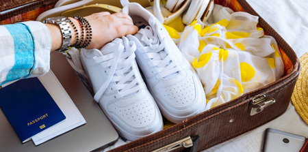 Ein gepackter Koffer, der offen da liegt und in den noch ein paar Schuhe gepackt werden.