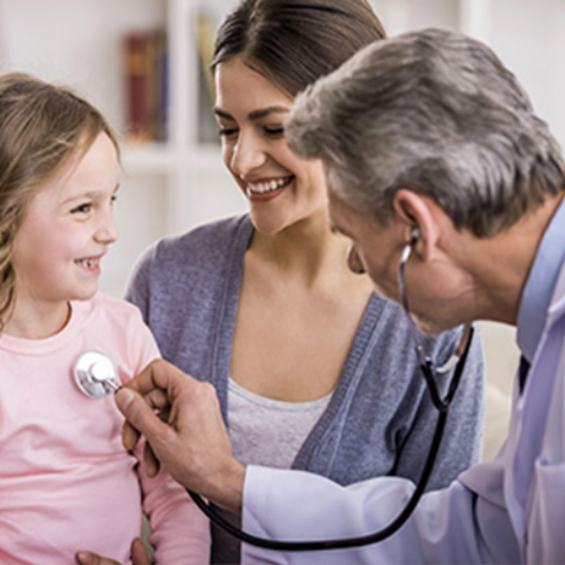 Doctor using a stethoscope on a little girl with her mother