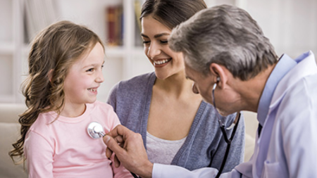 Doctor using stethoscope on a little girl with her mother