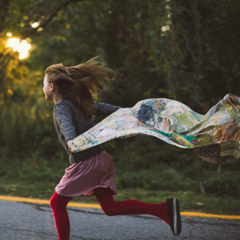 Girl running down the road with a blanket